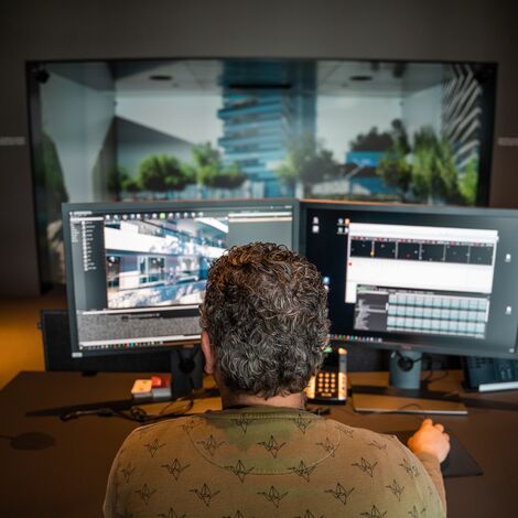 Expert creating a virtual building behind two computer screens.