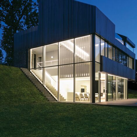 Casa privata ben illuminata con ampie superfici vetrate di notte.