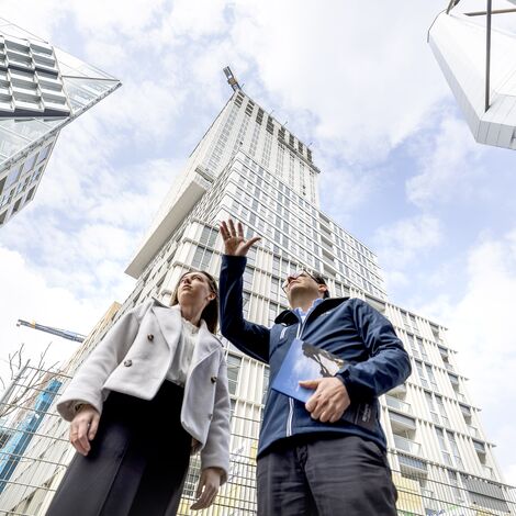 Uomo e donna indicano e parlano di edifici alti.