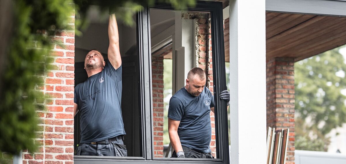 Due installatori posano nuovi profili in alluminio in un’abitazione ristrutturata. 