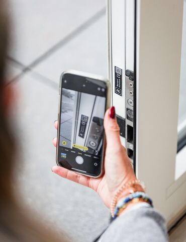 ChatGPT ha detto:Mano che tiene uno smartphone vicino a un codice QR su un profilo finestra bianco.