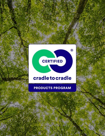 Logo Cradle to Cradle davanti alle cime verdi degli alberi.