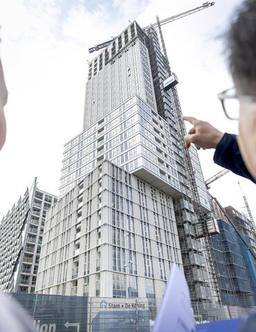 Uomo e donna indicano un progetto di edificio alto grigio in costruzione.