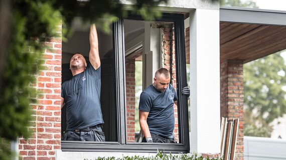 Due installatori posano nuovi profili in alluminio in un’abitazione ristrutturata. 