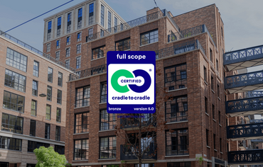 The Cradle to Cradle logo in front of red brick mid-rise buildings.