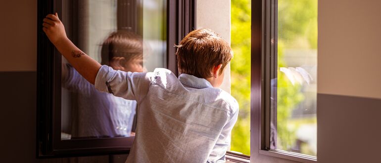 Child looking out of an open window.